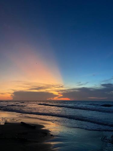 um pôr do sol na praia com o oceano em Bahía Santamaría em Moñitos