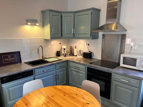 une cuisine avec des placards bleus et une table en bois dans l'établissement Appartement chic et cosy, à Épernay