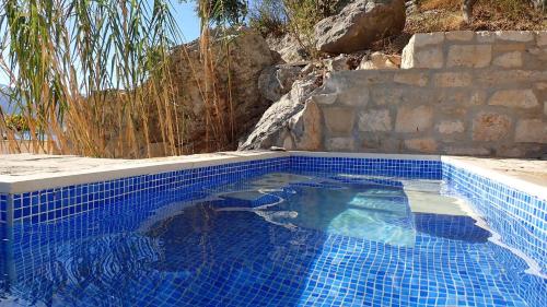 a blue tile swimming pool with a stone wall at Apartments Kuća Nebeska in Viganj