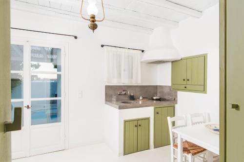 a kitchen with green and white cabinets and a table at Thalassitra Private Pool Suites in Adamas