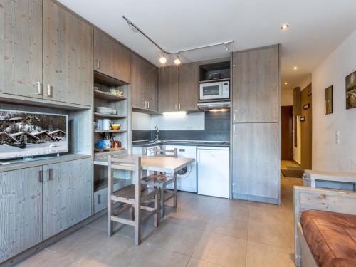 une cuisine avec des armoires en bois et une table en bois dans l'établissement Superbe studio rénové avec balcon, au pied des pistes, en plein cœur de Val-d'Isère - FR-1-694-299, à Val dʼIsère