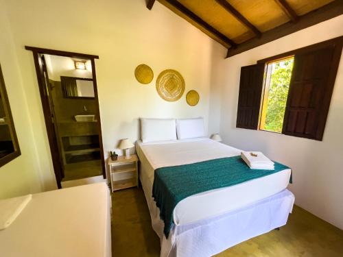 a bedroom with a white bed and a window at Pousada Beira Mar in Caraíva