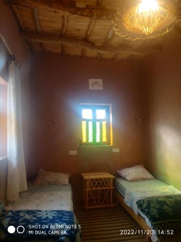 two beds in a room with a window at auberge restau tombouctou in Aït Ben Haddou