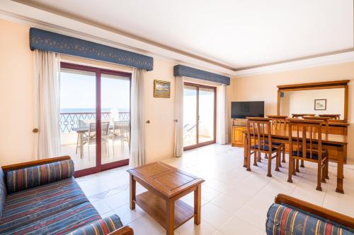 a living room with a couch and a dining room at Frente ao Mar - 2 quartos - wi-fi in Armação de Pêra