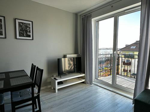 a living room with a television and a table and a balcony at Apartament Szczecin in Szczecin