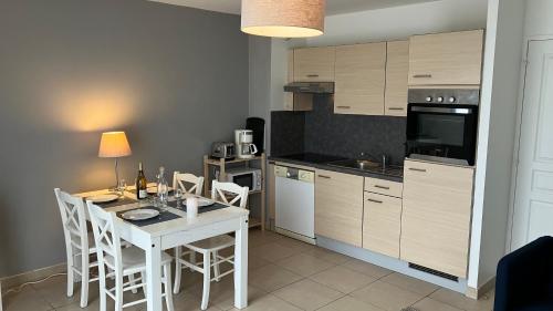 Il comprend une cuisine avec une table et des chaises blanches ainsi qu'une cuisine équipée d'une cuisinière. dans l'établissement F50 Ferme de Deauville 1 CH rez-de-jardin avec escalier, à Saint-Arnoult