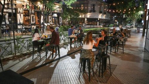 Loft Espectacular Céntrico con Garaje في روزاريو: مجموعة من الناس يجلسون على الطاولات في شارع المدينة