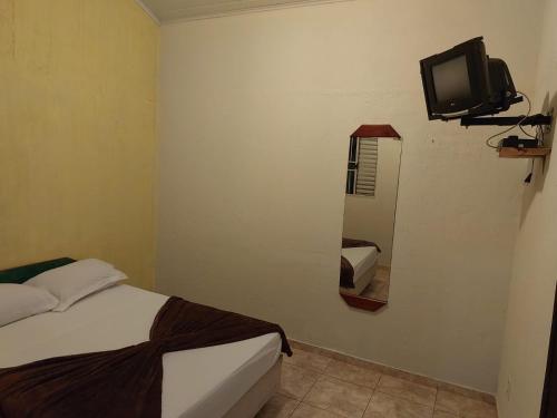 um quarto com uma cama e uma televisão na parede em Pousada por do soll em Serra do Cipó