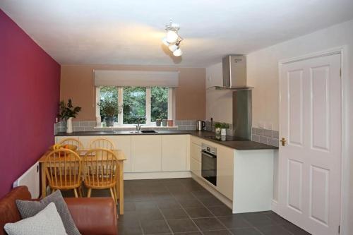 a kitchen with white cabinets and a table and chairs at The Cosy West Wing, dog friendly in Martham