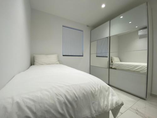een witte slaapkamer met een bed en een spiegel bij A52 - Apartment with Sea and Country Views in Mellieħa