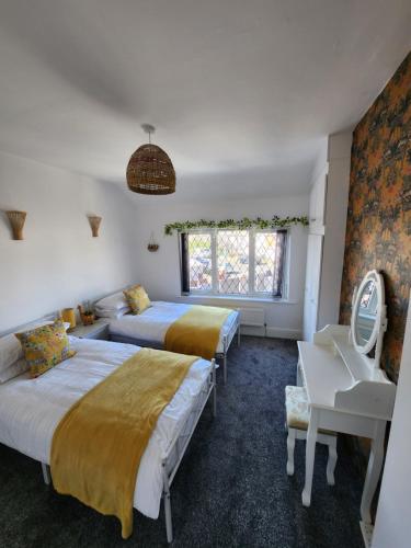 1 dormitorio con 2 camas, escritorio y ventana en Delightful newly renovated 3-bed house with garden beach hut en Blackpool