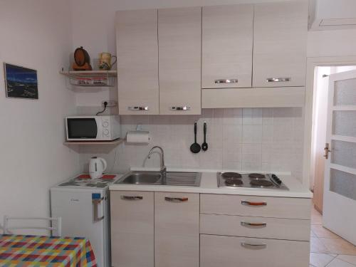 a small kitchen with white cabinets and a sink at Grazioso Monolocale Bellagio in Bellagio