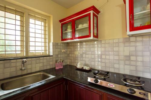a kitchen with red cabinets and a sink at Wind Surf Beach House in Alleppey