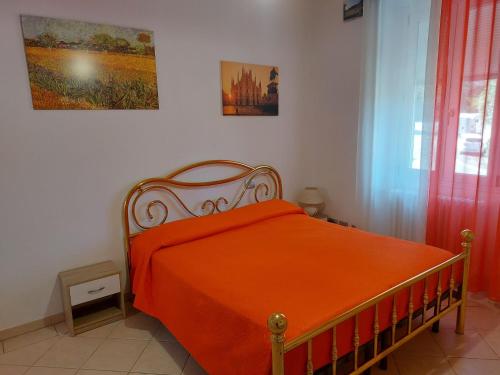 a bedroom with a bed with an orange blanket at Grazioso Monolocale Bellagio in Bellagio
