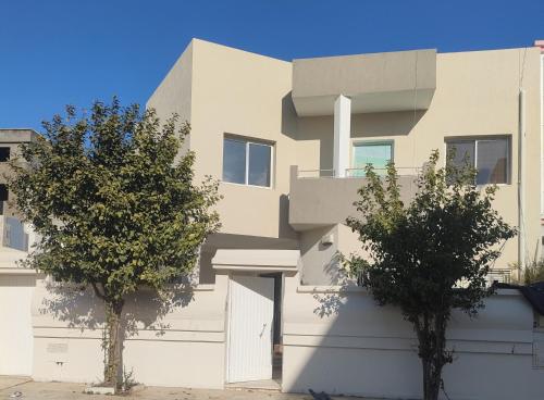 two trees in front of a white building at Tiba soliman plage in Nabeul