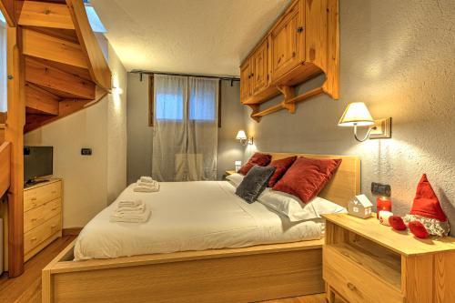 ein Schlafzimmer mit einem großen Bett mit weißer Bettwäsche und roten Kissen in der Unterkunft Casa Julie - CIR COURMAYEUR 0157 - in Courmayeur