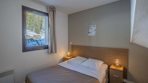 a bedroom with a bed with a window and two lamps at Madame Vacances Les Terrasses De Véret in Flaine