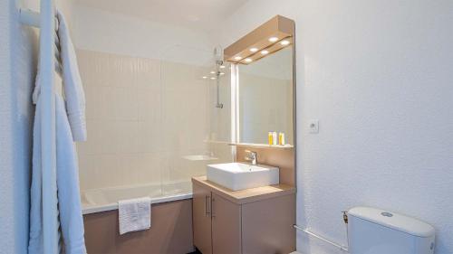 a bathroom with a sink and a toilet and a mirror at Madame Vacances Les Terrasses De Véret in Flaine