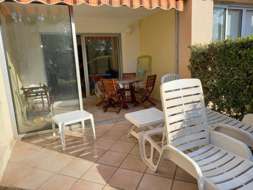 um pátio com cadeiras e uma mesa e cadeiras em Les Hauts du Golf Rez de jardin Piscine Tennis em Saint-Raphaël