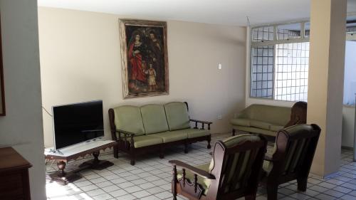 a living room with green chairs and a tv at Hotel Gaivota in Recife