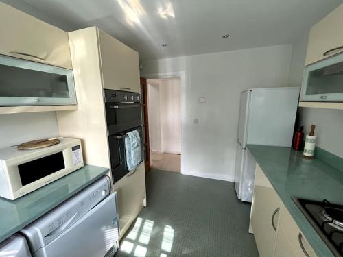 a kitchen with a microwave oven and a refrigerator at The Annexe at Firs House in Bedford