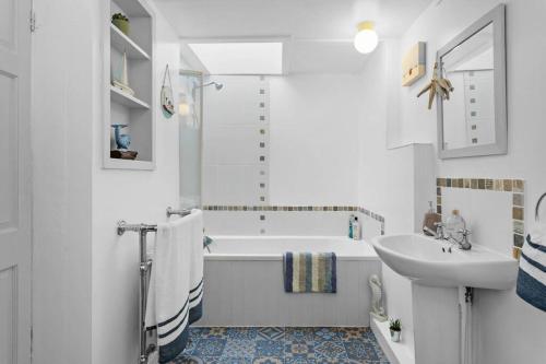 La salle de bains blanche est pourvue d'une baignoire et d'un lavabo. dans l'établissement Family Tides Brixham, à Brixham