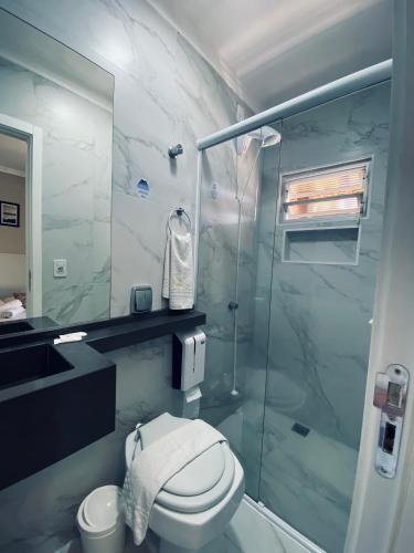 uma casa de banho com um WC e uma cabina de duche em vidro. em Hotel Lorimar em Penha