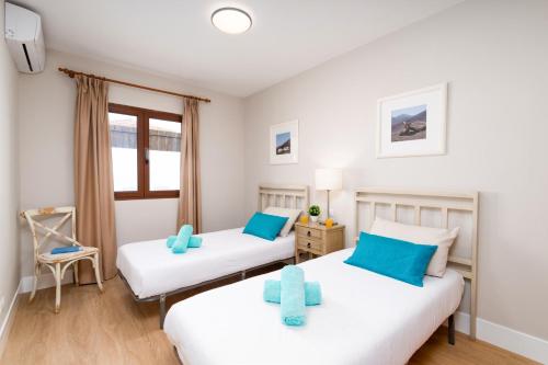 a bedroom with two beds and a window at Villa Caleta Del Sol by Villa Plus in Caleta De Fuste
