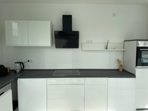 a white kitchen with white cabinets and a microwave at 4 ZKB Neubauwohnung mit Stil in Bielefeld