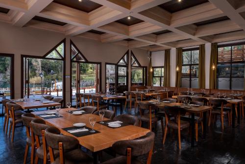 a restaurant with wooden tables and chairs and large windows at Bahía Manzano Resort in Villa La Angostura