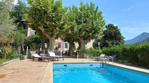 una piscina en un patio con sillas y árboles en Mas Bella Vida en Puget-Théniers