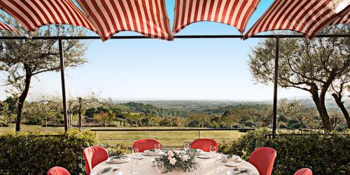 a table with red chairs and umbrellas with a view at L'Isola Di Rosa - Relais & Hotel di Charme in Cerveteri