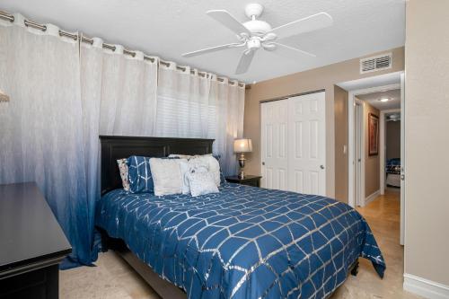 a bedroom with a blue bed with a ceiling fan at Tropical Oasis 809 in Naples