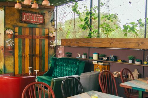 un restaurante con un banco verde, mesas y sillas en Velvet Hostal La novena, en Santa Ana
