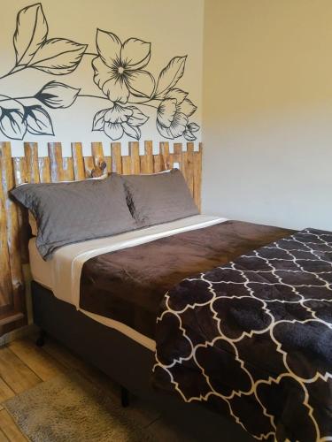 a bedroom with a bed with a flower mural on the wall at Recanto das Glicínias in Monte Verde