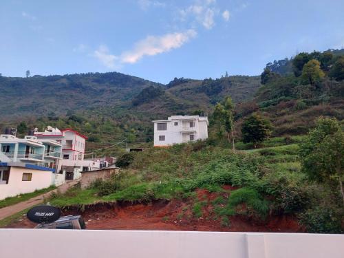 a group of houses on a hill with mountains at Kodai Diva Inn - Home Stay in Kodaikānāl