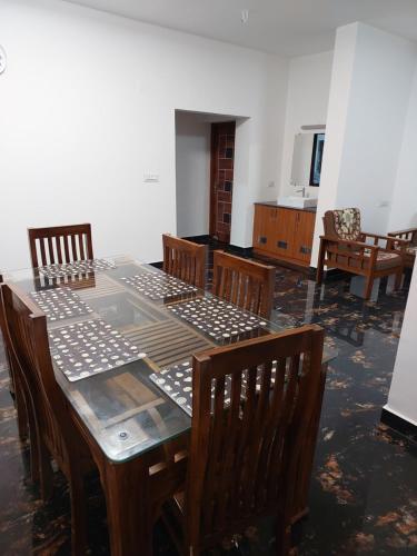 a dining room with a table and wooden chairs at Kodai Diva Inn - Home Stay in Kodaikānāl