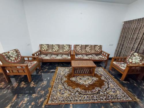 a room with four chairs and a table and a rug at Kodai Diva Inn - Home Stay in Kodaikānāl