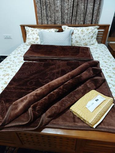 a brown blanket laying on top of a bed at Kodai Diva Inn - Home Stay in Kodaikānāl