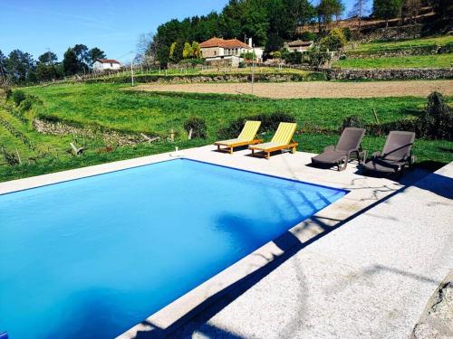 a swimming pool with two chairs and a couple of chairs at Casa Cabreiros de Baixo in Melgaço
