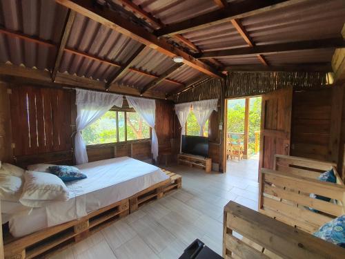 une chambre avec un lit et une télévision dans l'établissement Cabañas la tierra prometida, à Cisneros