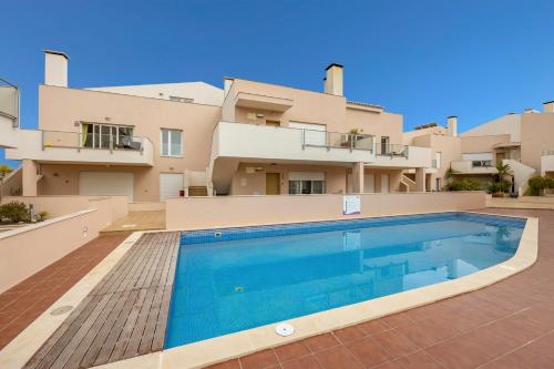 a villa with a swimming pool in front of a building at Burgau Beach House in Burgau