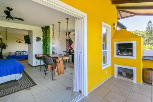 a living room with a yellow wall and a dining room at Penareia Floripa Beach Hotel in Florianópolis