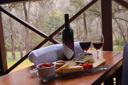 una bottiglia di vino e un piatto di formaggio e bicchieri da vino di Beyonderup Falls Adult Retreat a Nannup