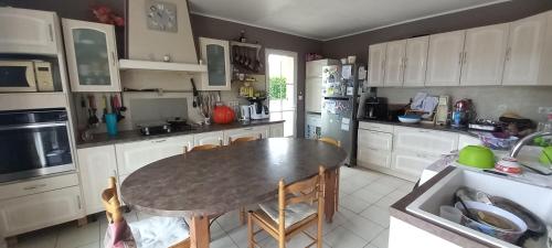 eine Küche mit einem Tisch und eine Küche mit weißen Schränken in der Unterkunft chambre familiale dans maison au calme in Segonzac