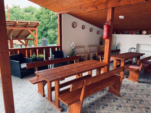 een patio met houten tafels en banken op een veranda bij Sátor-Hegy Vendégház in Abaújszántó