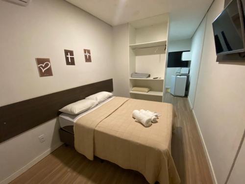 a small bedroom with a bed and a refrigerator at Hotel Smart in Mogi Mirim