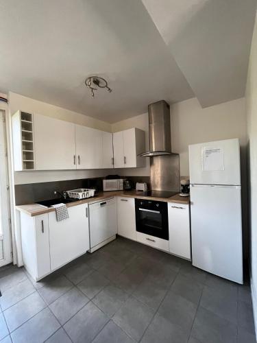 a kitchen with white cabinets and a white refrigerator at Gîte du Coudray in Neuillé-Pont-Pierre