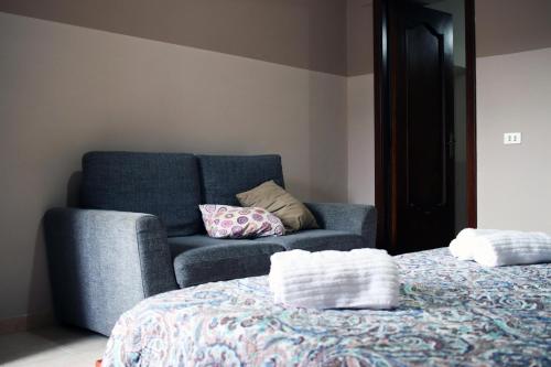 B&b Vista Etna في رانداتسو: أريكة زرقاء مع وسائد فوق السرير