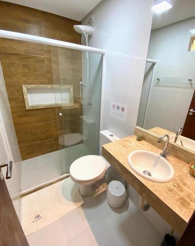 a bathroom with a shower and a toilet and a sink at Pousada Rosa do Mar in Gamboa